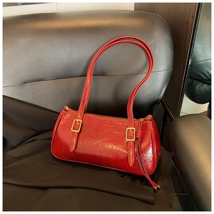 Détail du sac sous l'aisselle en cuir verni rouge avec texture vintage et boucles d'or