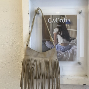 Detailed close-up of light brown suede fringe bag with bohemian knotted shoulder strap