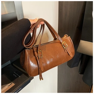 Détail du sac cylindre vintage en cuir marron avec texture plissée et boucles dorées