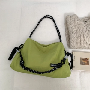 Gros plan du sac en nylon vert montrant la bandoulière en corde épaisse et le nœud