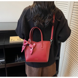 Dettaglio della borsa tote rossa con foulard di seta e logo dorato per il lavoro