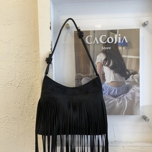 Detail of black suede shoulder bag with long fringes and bohemian knotted strap