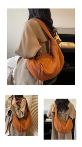 Detail view of the orange crescent bag showing unique pleated fabric and long zipper detail