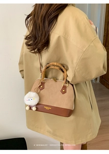 Detail of retro shell handbag with contrast colors and bamboo handle on khaki trench coat