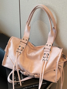 Minimalist soft pink leather shoulder bag with vintage drawstring details and dark metal buckle