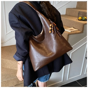 Detail of vintage brown tote bag featuring texture leather and wooden bead tassel ornament