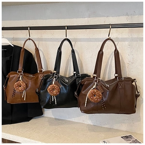 Three leather travel tote bags in brown, black, and coffee displayed on a metal rack