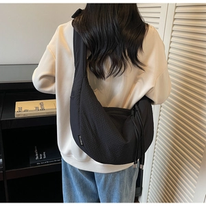 Detail of minimalist black nylon crescent bag with adjustable drawstring and side label