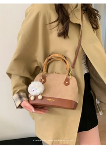 Detail of vintage shell bag with bamboo handle, beige contrast leather, and plush charm