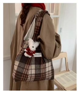 Close-up of brown plaid wool tote bag with cute white plush bear pendant detail