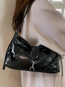 Elegante borsa baguette in pelle verniciata nera con fibbia argento indossata da modella
