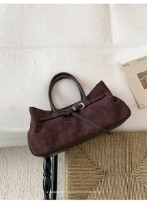 Close-up of vintage brown suede tote bag featuring leather strap and metal buckle detail