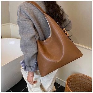 Detail showing the brown large tote bag with brand logo and beaded tassel charm