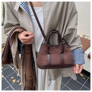 Detail of a brown leather patchwork handbag with a vintage design and metal buckle