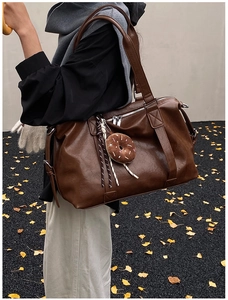 Detail view of large dark brown leather tote bag with cute donut charm on a shoulder strap