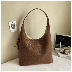 Detail of a large leopard print tote bag with wooden bead tassels in a stylish setting