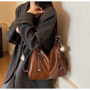 Close-up of vintage brown hobo bag featuring silver zippers and baseball charm detail