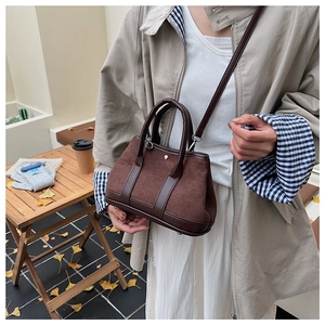 Detailed shot of retro brown suede handbag with smooth leather stitching on a wooden table