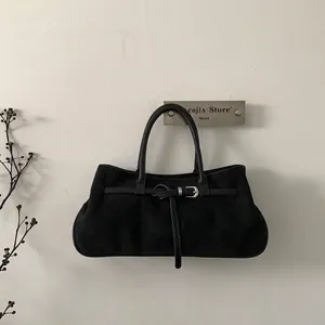 Detailed view of the matte black suede tote bag with decorative buckle and round handles