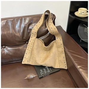 Detail of a brown suede hobo bag featuring wide straps with stylish metal eyelet accents
