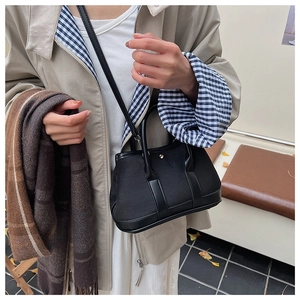 Detail of minimalist black canvas and leather crossbody bag in an autumn street style look