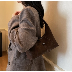 Detail of vintage dark brown suede hobo bag with metal buckle on a tweed blazer