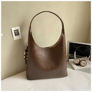 Detailed shot of large brown Hobo tote with wide shoulder strap and wooden bead charm