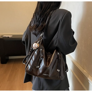 Close-up of gloss leather tote bag with tassel zippers and baseball charm pendant