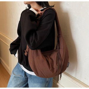 Detail of dark brown crescent bag with fringe on model showing size and texture