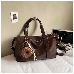 Detailed close-up of dark brown PU leather tote bag with plush donut and chocolate charms