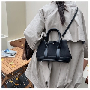 Detail of black canvas and leather tote bag styled in a minimalist autumn scene