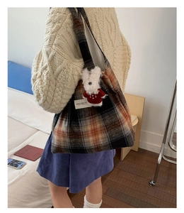 Detail of large plaid tote bag in wool material featuring a cute bunny charm on the strap