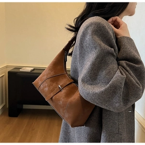 Detail view of retro brown suede shoulder bag with decorative stitching and silver buckle