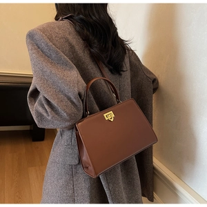 Vue détaillée du sac cabas en cuir marron avec fermoir tournant doré et poignée chic