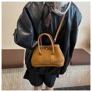 Close-up of brown suede tote bag featuring leather trim and detachable shoulder strap