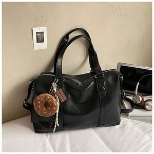 Detail of a black large-capacity tote bag with zipper closure and cute charms