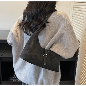 Detail of minimalist black matte suede hobo bag with silver buckle and adjustable strap