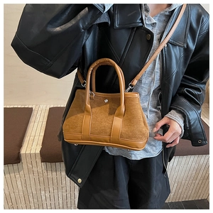 Detail of vintage brown suede crossbody bag with smooth leather trim and detachable strap