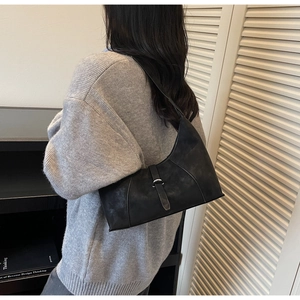 Detail of black matte suede crescent bag showing the silver buckle and shoulder strap texture