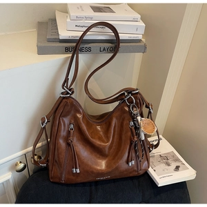 Close-up of retro brown leather tote with tassel zippers and polished silver metal ring