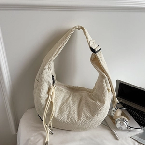 Close-up of cream waffle-textured fabric and adjustable buckle on half-moon bag