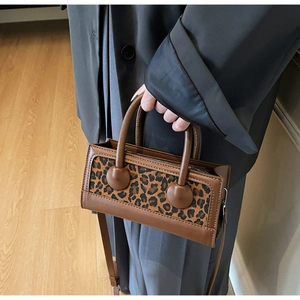 Detail of trendy leopard print handbag with brown leather handles and shoulder strap