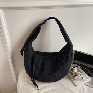 Close-up of black waffle-textured crescent bag featuring drawstring detail and wide strap
