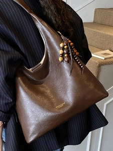 Deep brown large leather hobo bag with wooden bead tassel charm on a fashion model