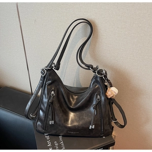 Close-up of black soft leather Hobo bag featuring dual tassel zippers and baseball charm