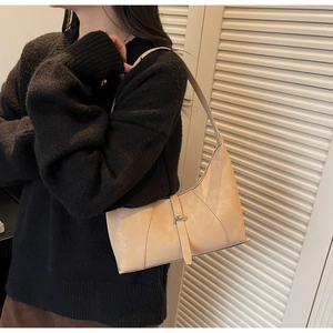 Detail of light beige suede crescent bag with metal buckle strap and asymmetrical design
