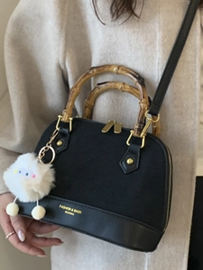 Retro black shell handbag with bamboo handles and white plush charm on model