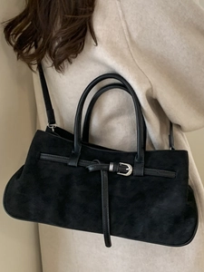 Matte black leather tote bag with top handles and shoulder strap shown on model