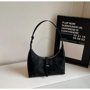 Detail of a black matte suede crescent bag with adjustable strap and metal buckle