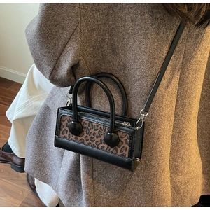 Chic leopard print crossbody bag worn over a dark blazer, showing side profile details